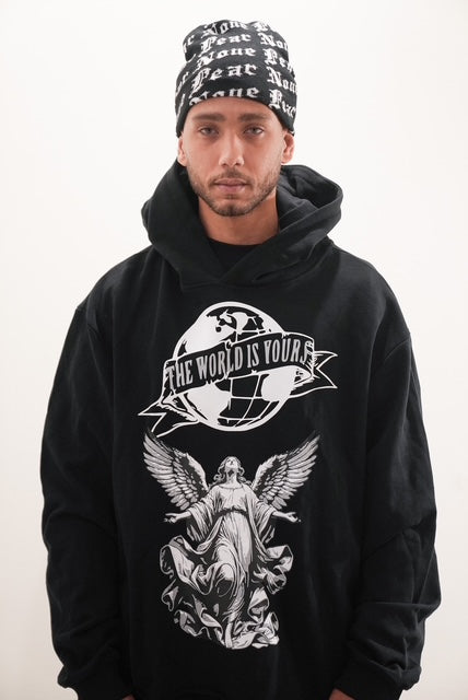 Person wearing a black hoodie with graphic design and a beanie on a white background